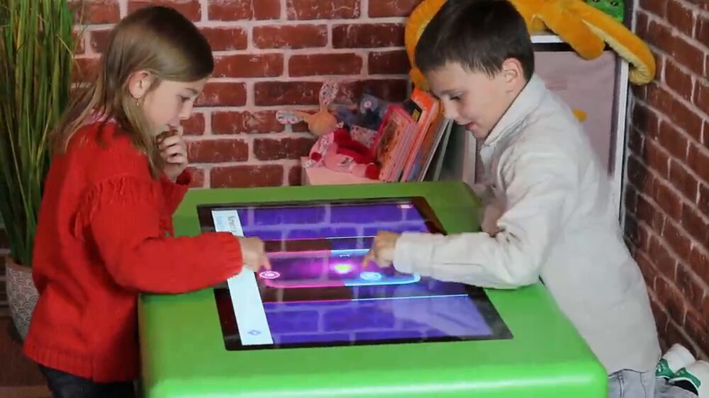Deux enfants jouent sur une table tactile Kiddyz